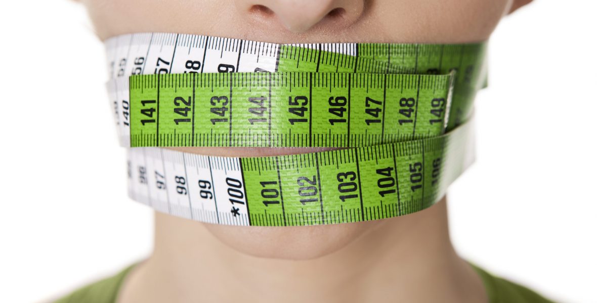 Portrait of a young  woman with a green measuring tape covering the mouth